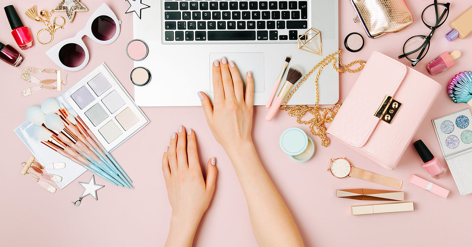 A woman using a laptop or smartphone with beauty products surrounding her