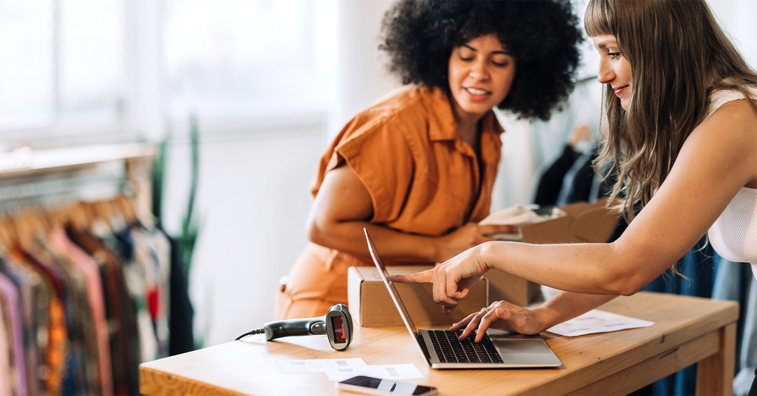 Two women looking at a laptop learning eCommerce web development terms