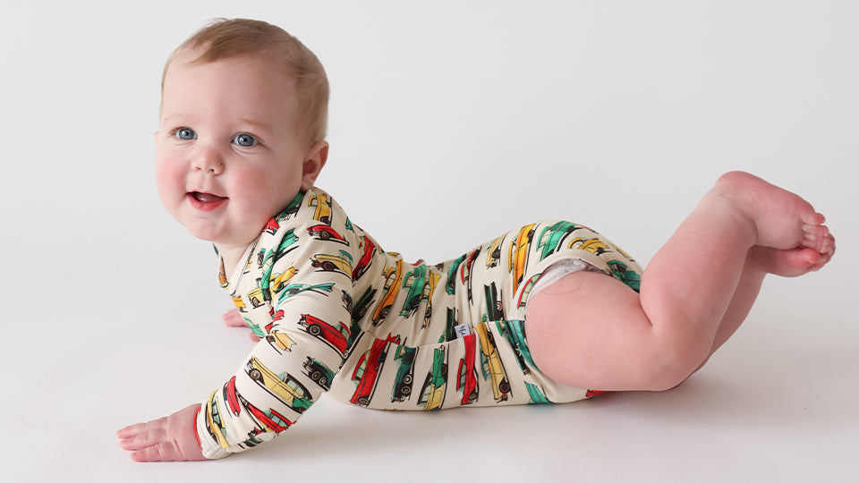 Smiling baby in vintage car print bamboo bodysuit from Autumn Moon Kids’ Clothing